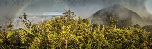 Panoramic photo of mountains covered by fog with rainbow in Digne in Kubor range, Papua New Guinea. In this region, one can only meet people from isolated local tribes