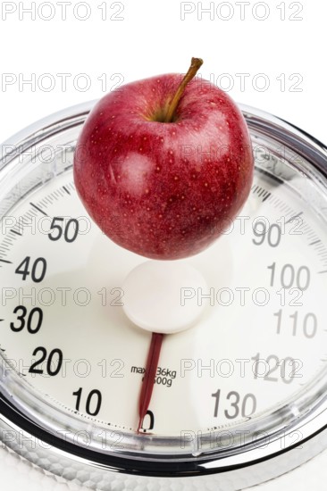 An apple lies on a bathroom scales. Symbolic photo for weight loss and a healthy, vitamin-rich diet. Austria