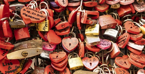 Verona, Italy, June 2022: background of heart-shaped locks on a wall, symbol of love forever