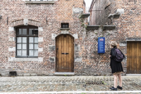 Tournai Doornik, Walloon Region, Belgium, 08 14 2019 Local tourist in summer dress looking at the facade and entrance of the Folklore museum
