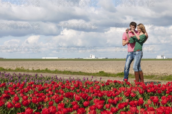 Young couple is taking pictures in Holland from flower fields