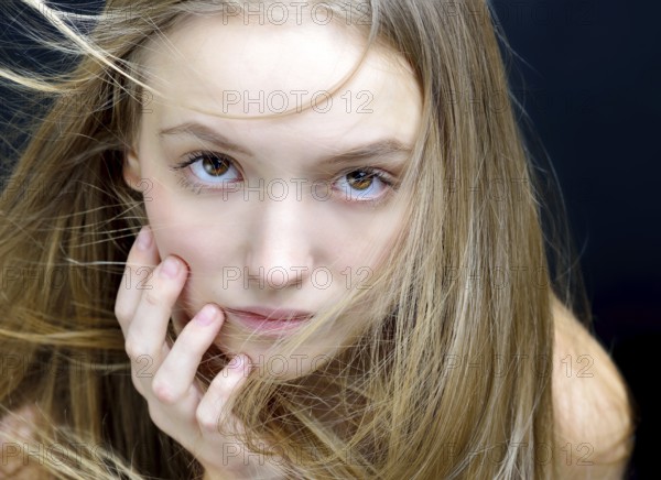 Portrait of the beautiful blonde woman with flying long hair. She is in the studio