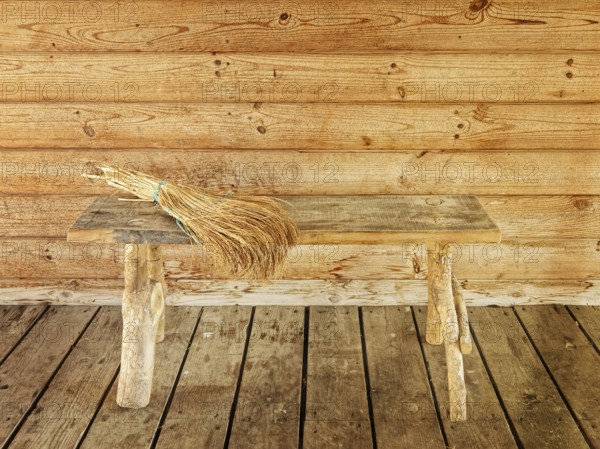 Bench and broom over it against wooden wall