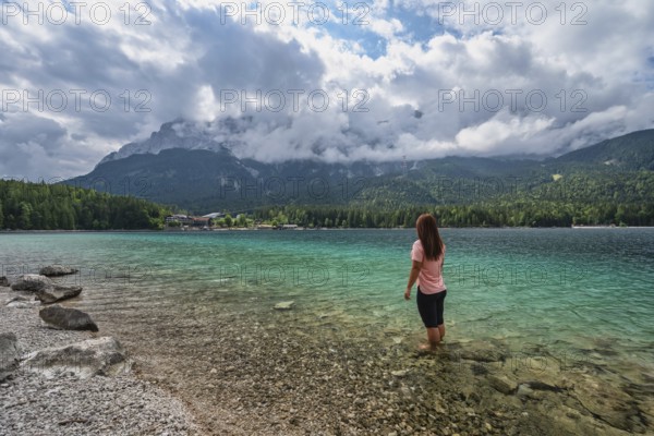 Zugspitze Peak top of Germany Alps mountain range and Eibsee Lake with woman tourist, Garmisch Partenkirchen Germany