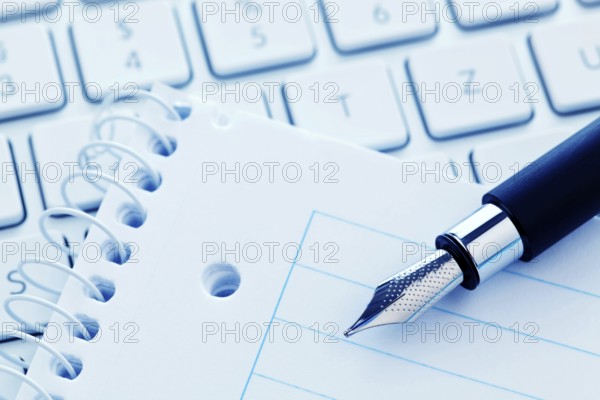 A notepad and the keyboard of a computer. Take notes and save them. Austria