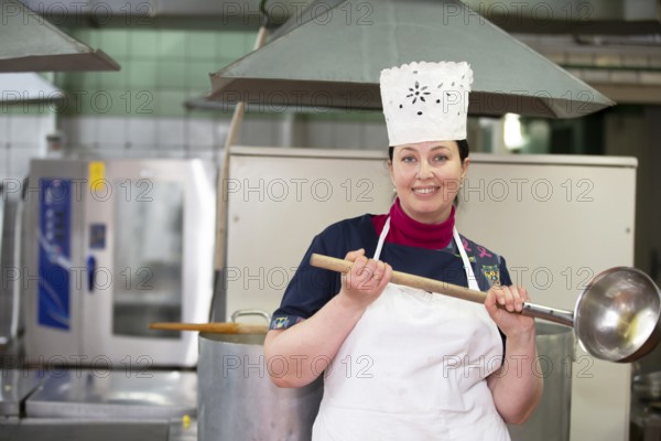 May 31, 2021 Belarus, Gomel, industrial kitchen. Chef in an industrial kitchen smiling and looking at the camera.Communal dining room