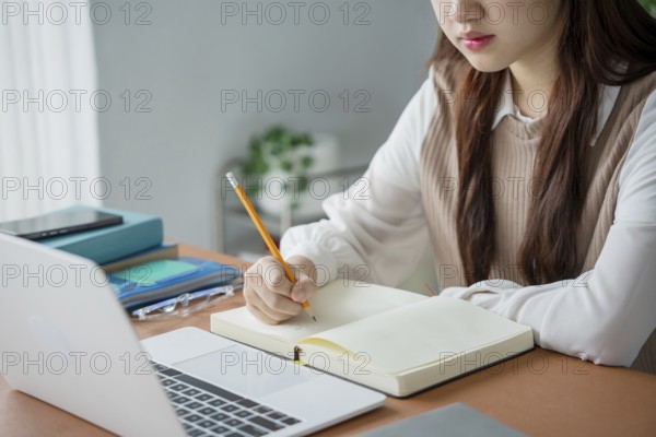 Asian woman using laptop to study student engaged in online learning at college