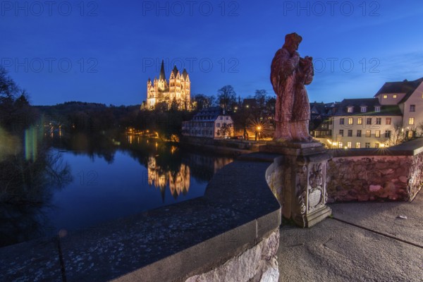 Beautiful landscape shot on the river Lahn, with many trees and bushes on the bank. Taken in the morning at sunrise. You can see the reflection in the river bank and the cathedral of Limburg, Hesse, Germany