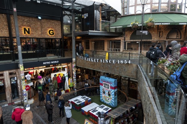 Shoppers at an elevated outdoor market with clothing stores and signs in the London Borough of Camden, Greater London, United Kingdom