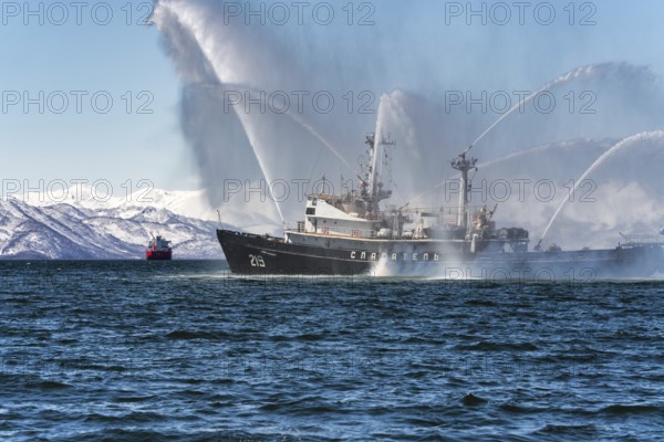 KAMCHATKA PENINSULA, RUSSIA, APR 27, 2019: Fire fighting and rescue ship of Pacific Fleet of Russia spraying water on sea for supporting emergency case of fire of warships, passengers and cargo ships
