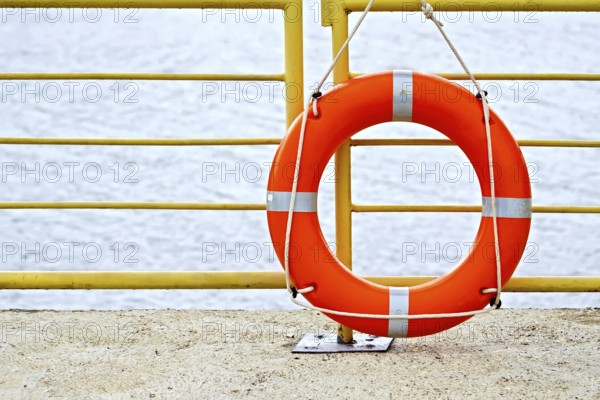 Lifebuoys red hanging on the yellow fence on the background of water