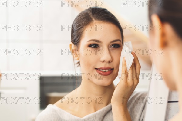 Beautiful young woman cleaning her face, removing make up with a cotton pad and micellar water. Skin care and beauty. Young beautiful woman cleaning her face.