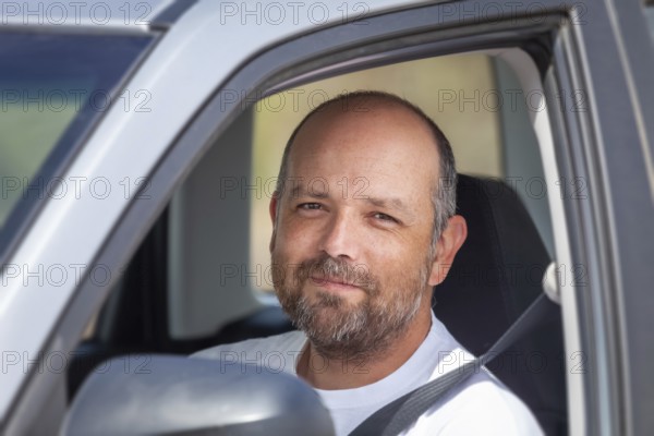An image of a bearded man sitting in his car