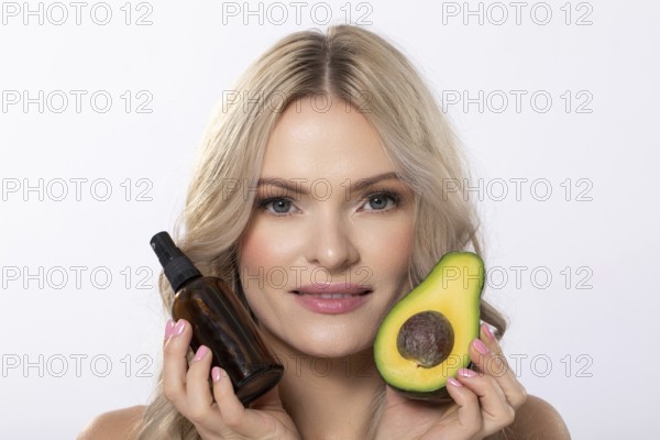 A model elegantly showcasing avocado along with beauty oil specifically designed for natural skincare routines