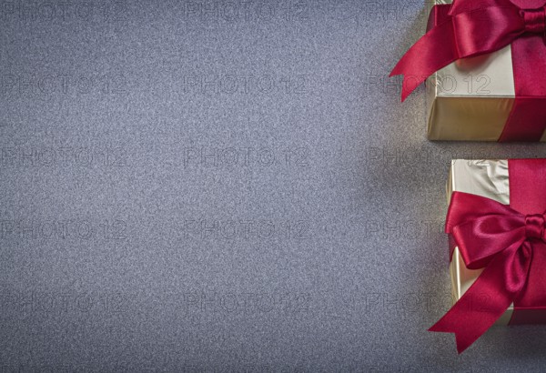 Boxed wrapped presents with red tapes on grey background copy space holidays concept