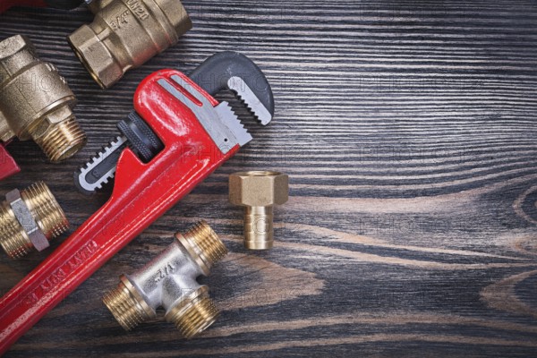 Set of monkey wrench brass connectors on wooden board plumbing concept