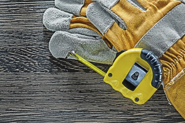 Tape measure pair of protective gloves on wooden board