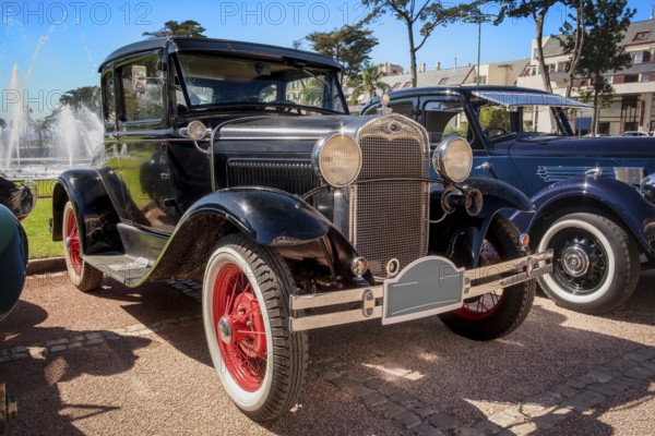 Lisbon, Portugal - Sep 29, 2024: View of classic Ford Model A or A-Model Ford or the A and A-bone in original black color parked on cobblestone road near other oldtimers during annual Classic Car Owners meeting on sunny day. Ford Motors, USA