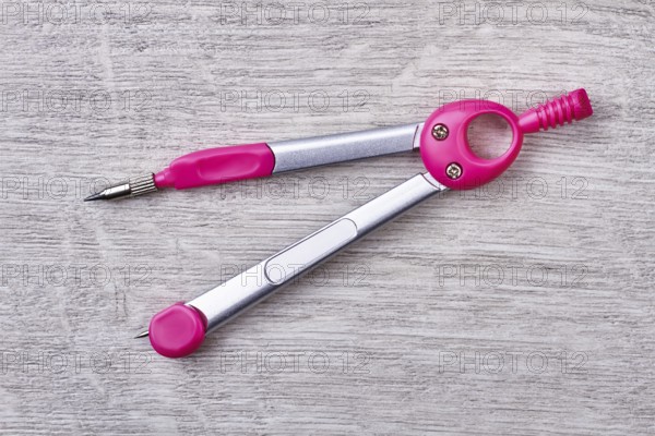 Pair of compasses on wood. Stationery on gray wooden backdrop. Equipment for school lessons