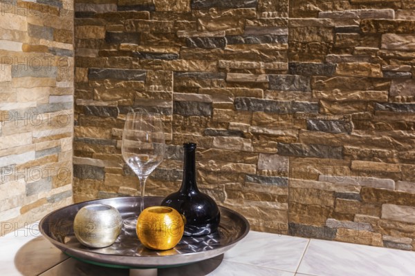 Still-life with a black glass jug, a transparent glass and two candlesticks. Background stone wall. Concept of artistic photography
