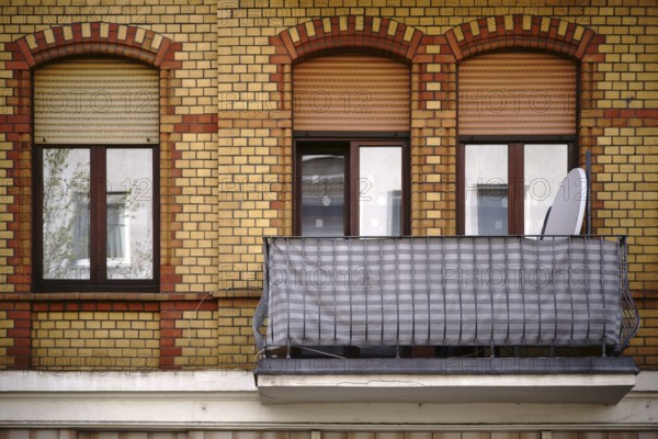 The façade of an old residential building with a clinker brick façade and a nostalgic balcony