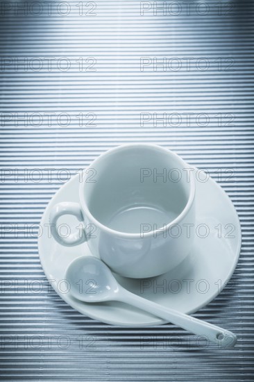 White ceramic cup saucer teaspoon on striped background