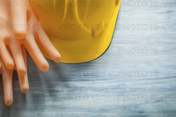 Pair of rubber insulating gloves building helmet on wooden board electricity concept