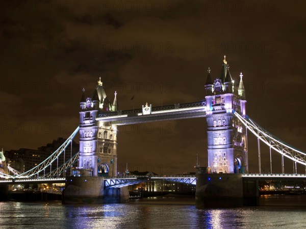 Bright lights of a historic bridge reflected in the calm river water, London, United Kingdom