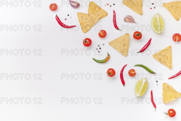 Creative Top view flat lay of fresh mexican food ingredients with tortilla nachos chips garlic pepper lime tomatoes on white table background with copy space. Food preparation cooking concept frame
