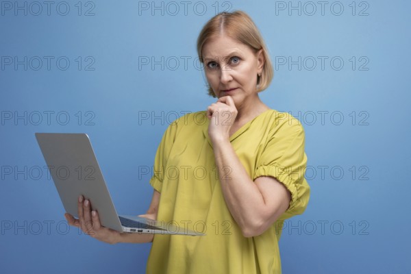 Pensive middle aged business woman freelancing using laptop and internet connection