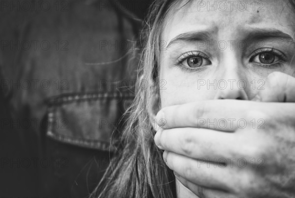 Man's hand covering mouth of scared young girl
