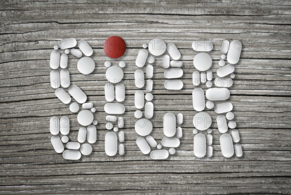 Conceptual Health Image Of Pills On A Wooden Table Spelling The Word Sick