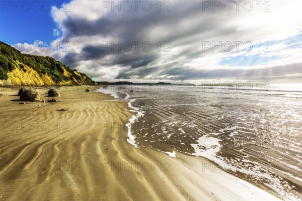 New Zealand. Moeraki's huge round boulders on a sandy beach. The Pacific ocean tide begins. The concept of ecological, exotic and phototourism