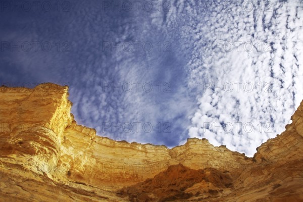 Edges of a canyon from dry sandstone on a background of the cloudy sky