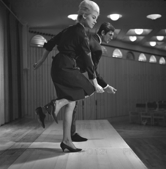 Dancing in the 1960s. The dance Hully Gully is being made popular and here are men and women dancing the new craze. Hully Gully was a type of unstructured line dance and consisted of a series of steps and was relatively simple and easy to execute. Hully Gully can be seen performed by actor John Belushi in the film Blues Brothers. Notice the typical BeeHive hairdo on the girl in front. Picture taken 1963
