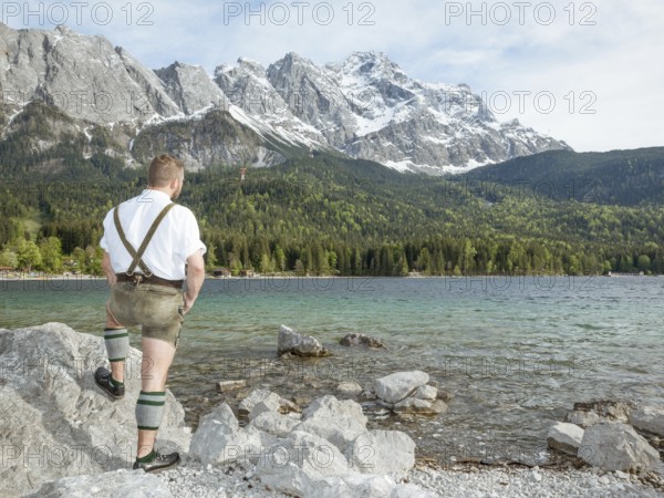 A traditional bavarian man at lake Eibsee with the Zugspitze mountain in the background
