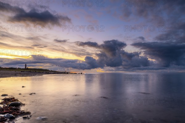 Atmospheric sunset landscape at the seaside with clouds and a lighthouse. Soft light at the sunset at the seaside with clouds and a lighthouse