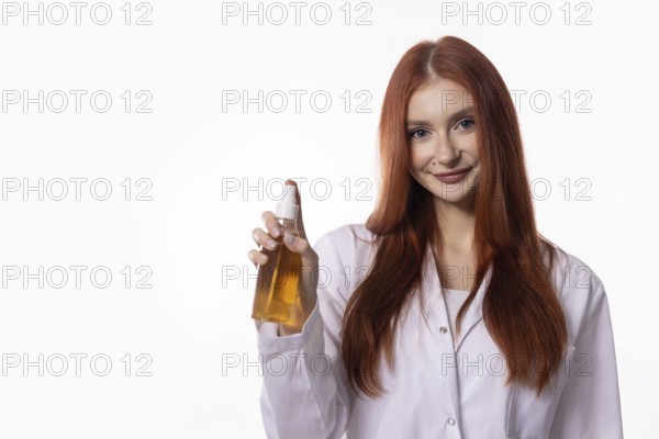 A confident woman in a lab coat showcases a nourishing oil in a professional setting, exuding expertise and style