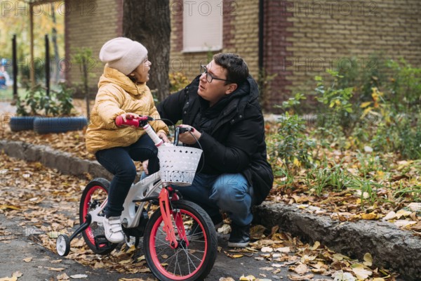 Father with daughter learning to ride the bike. Autumn weekend day in the city neighbourhood. Childhood moments with parents. parenthood.