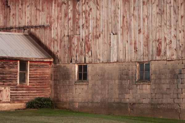 A rustic barn wall with wooden planks and brick foundation in rural setting in Ontario, Canada, North America