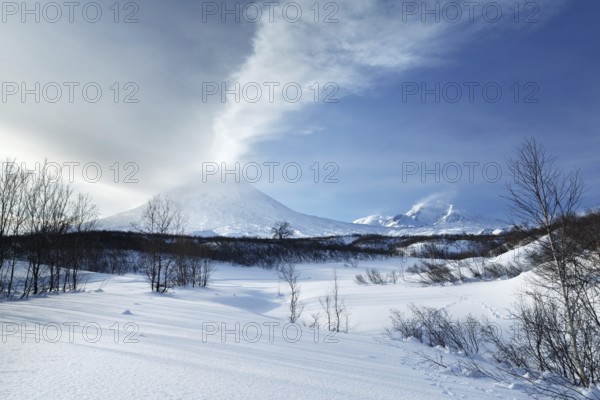 Beautiful volcanic landscape of Kamchatka Peninsula: evening view of eruption active Klyuchevskoy Volcano (Klyuchevskaya Sopka), emission from crater of volcano plume of gas, steam and ashes. Eurasia, Far East, Russia, Kamchatsky Krai