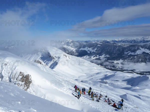 Situation on the summit of Haengst in Soerenberg, Switzerland, on a sunny winter day: A group of ski tourers having a rest
