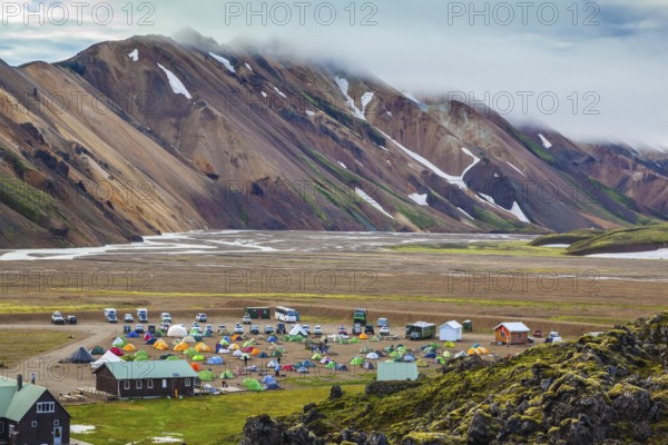 Pink and green rhyolite mountains surround the flat valley of the National Park Landmannalaugar. Big tourist camp is located in the valley of the park