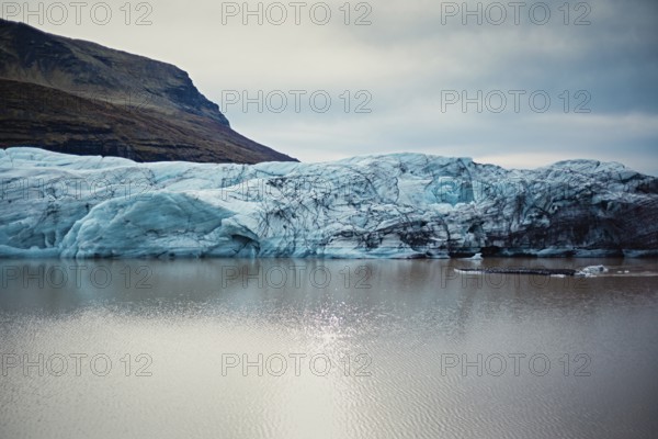 Massive blue glacier reflecting in a calm lake surrounded by rocky mountains, iceberg, glacier, snow, ice rock, ice diamont, glacier lagoon, nature, snow, diamont beach, Iceland