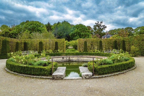 Picturesque round pool in the park greenhouse. Thepossession of Puss in Boots. Graceful bosquets surround the pool in Breteuil Park. Castle of Breteuil. France