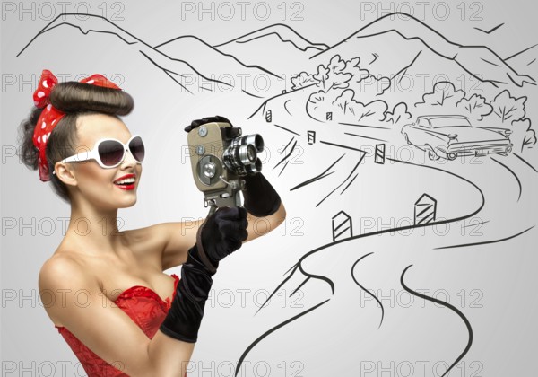 Glamorous pin up girl filming nature and landscape with an old retro cinema 8 mm camera, standing in front of a street on a grey sketchy background