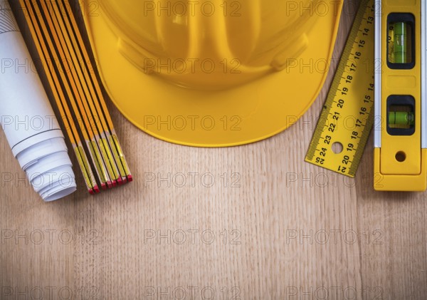 Protective helmet instruments of measurement blueprints and construction level on wooden board architecture and building concept