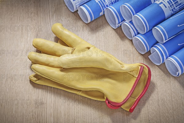 Blue construction plans leather protective gloves on wood board maintenance concept