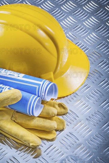 Blue blueprints hard hat safety gloves on fluted metal plate construction concept