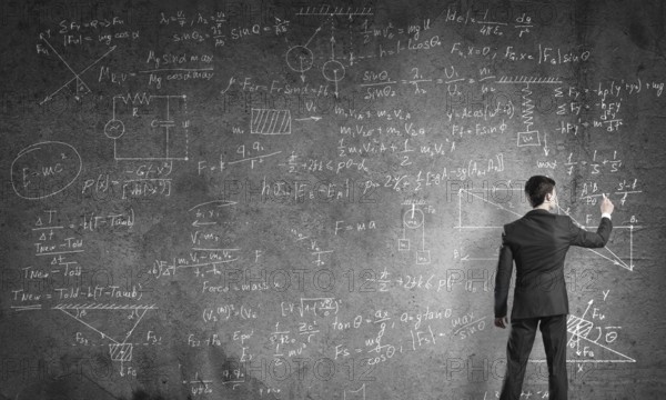Man in suit standing with back and drawing physics formulas